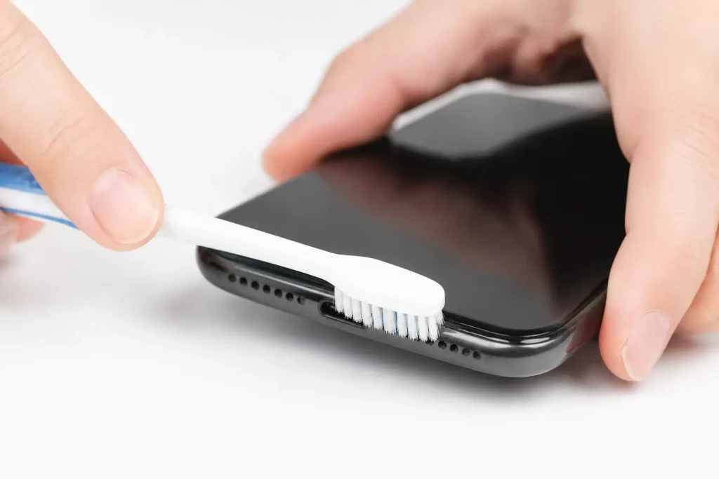 Cleaning a phone speaker grill with a soft dry toothbrush