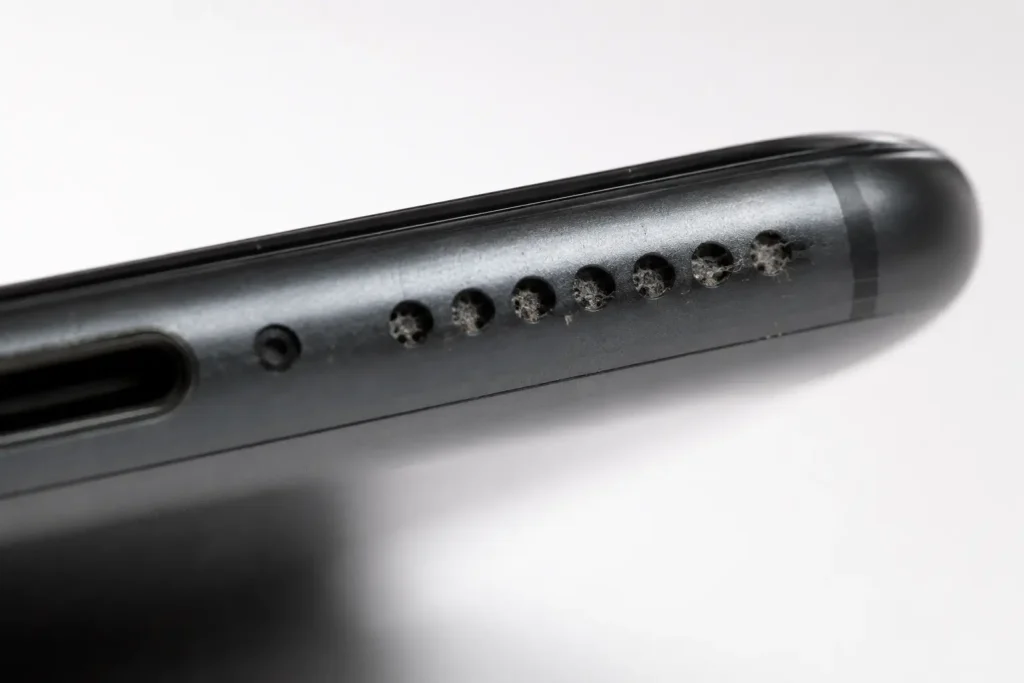 Dust and lint clogging a phone speaker grill, a common cause of muffled sound